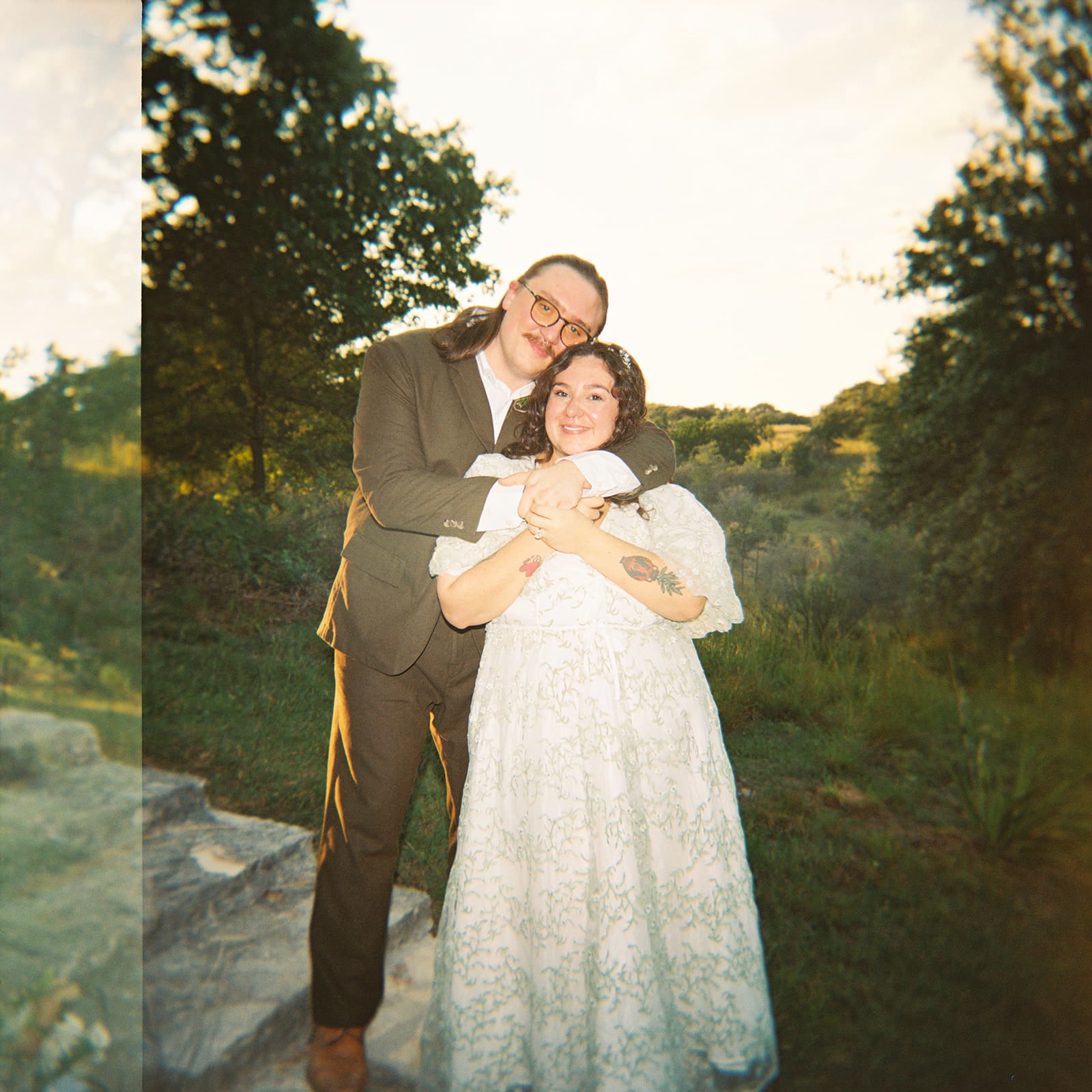 A couple dressed in formal attire takes elopement photos while standing outdoors on a sunny day for a texas hill country elopement