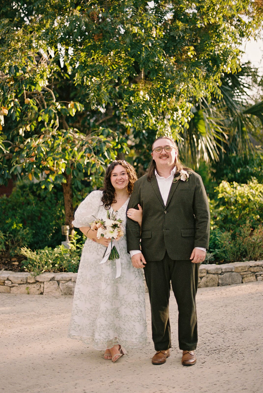 A couple dressed in formal attire takes elopement photos while standing outdoors on a sunny day for a texas hill country elopement 