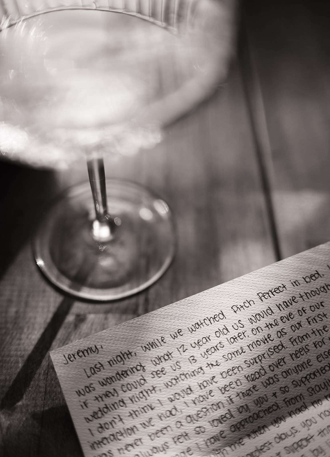 A handwritten note on textured paper reads "Crimson, I love you" with more cursive text below, partially obscured by shadows and a glass object in the upper right.