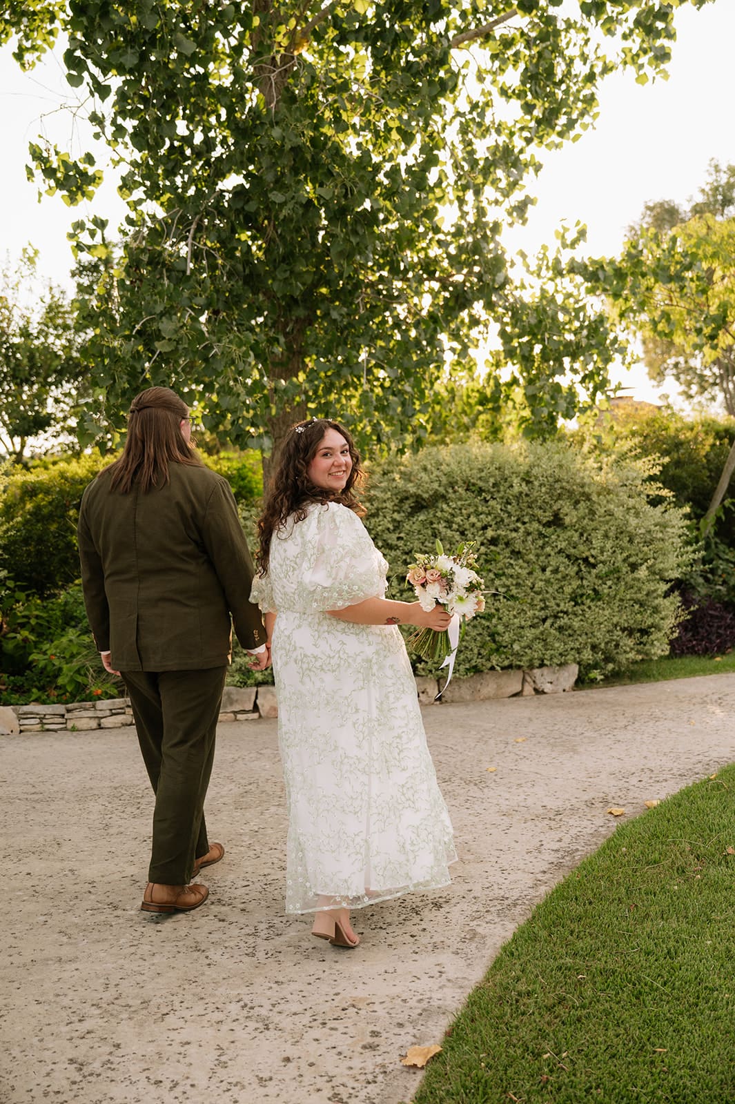 A couple dressed in formal attire takes elopement photos while standing outdoors on a sunny day for a texas hill country elopement 
