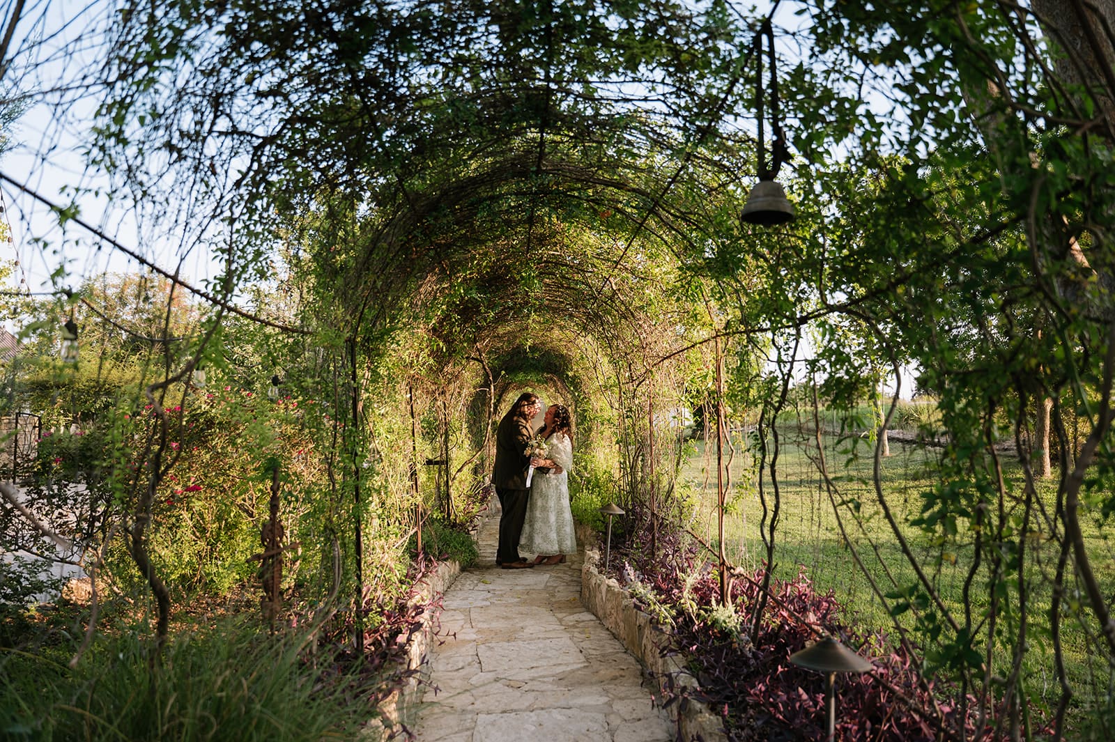 A couple dressed in formal attire takes elopement photos while standing outdoors on a sunny day for a texas hill country elopement