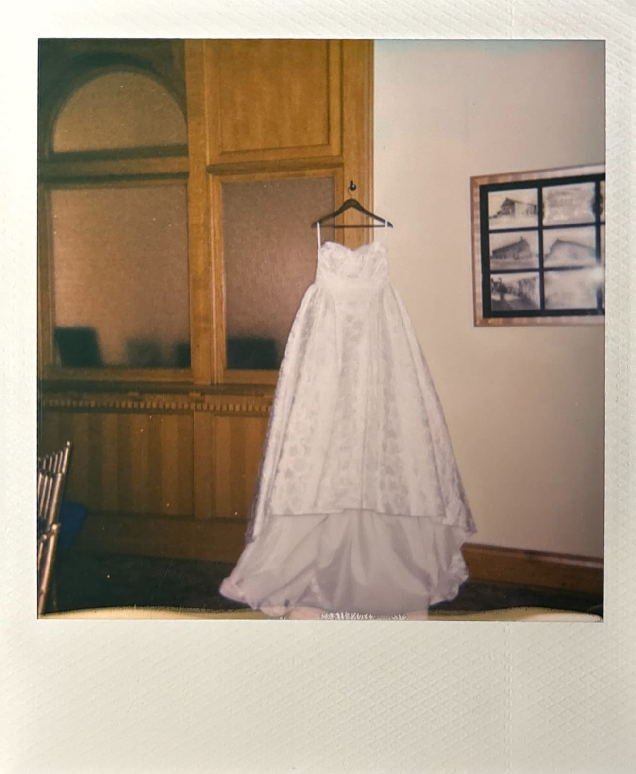 A woman in a dark dress helps another woman in a white gown adjust the back of her dress in an indoor setting for a Wedding at The Ashton Depot in Fort Worth