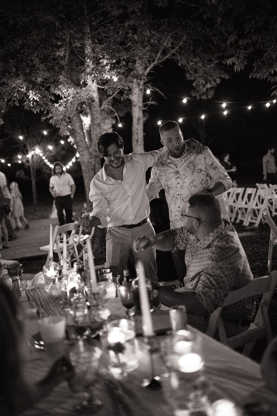 A bride and groom dance together at an outdoor night wedding reception, surrounded by guests and string lights for a backyard wedding