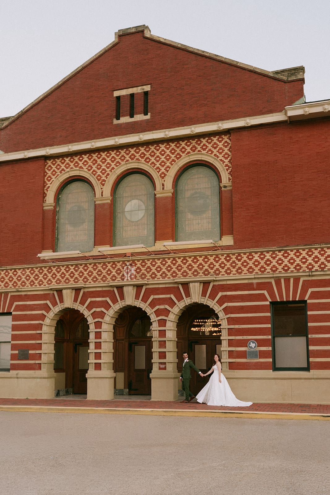bride and groom take wedding portaits outside of The Ashton Depot in Fort Worth