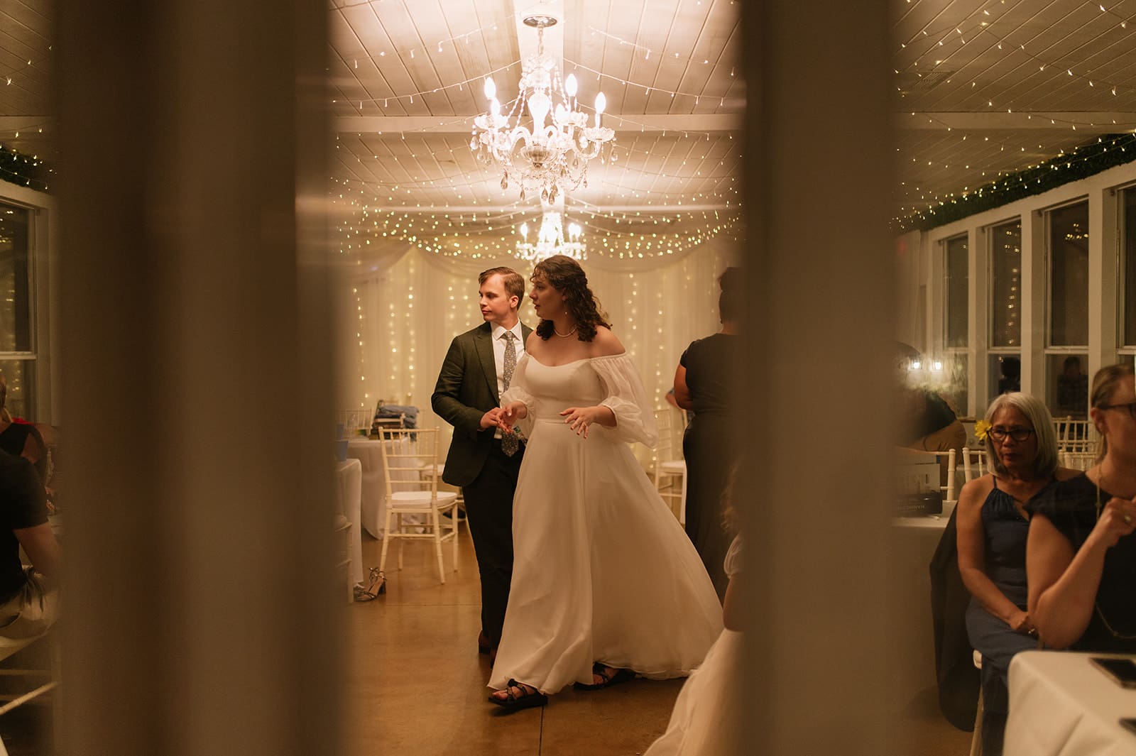 A bride and groom dance together in a warmly lit, decorated room as guests sit at tables and watch at Magnolia Terrace in Frisco, Tx