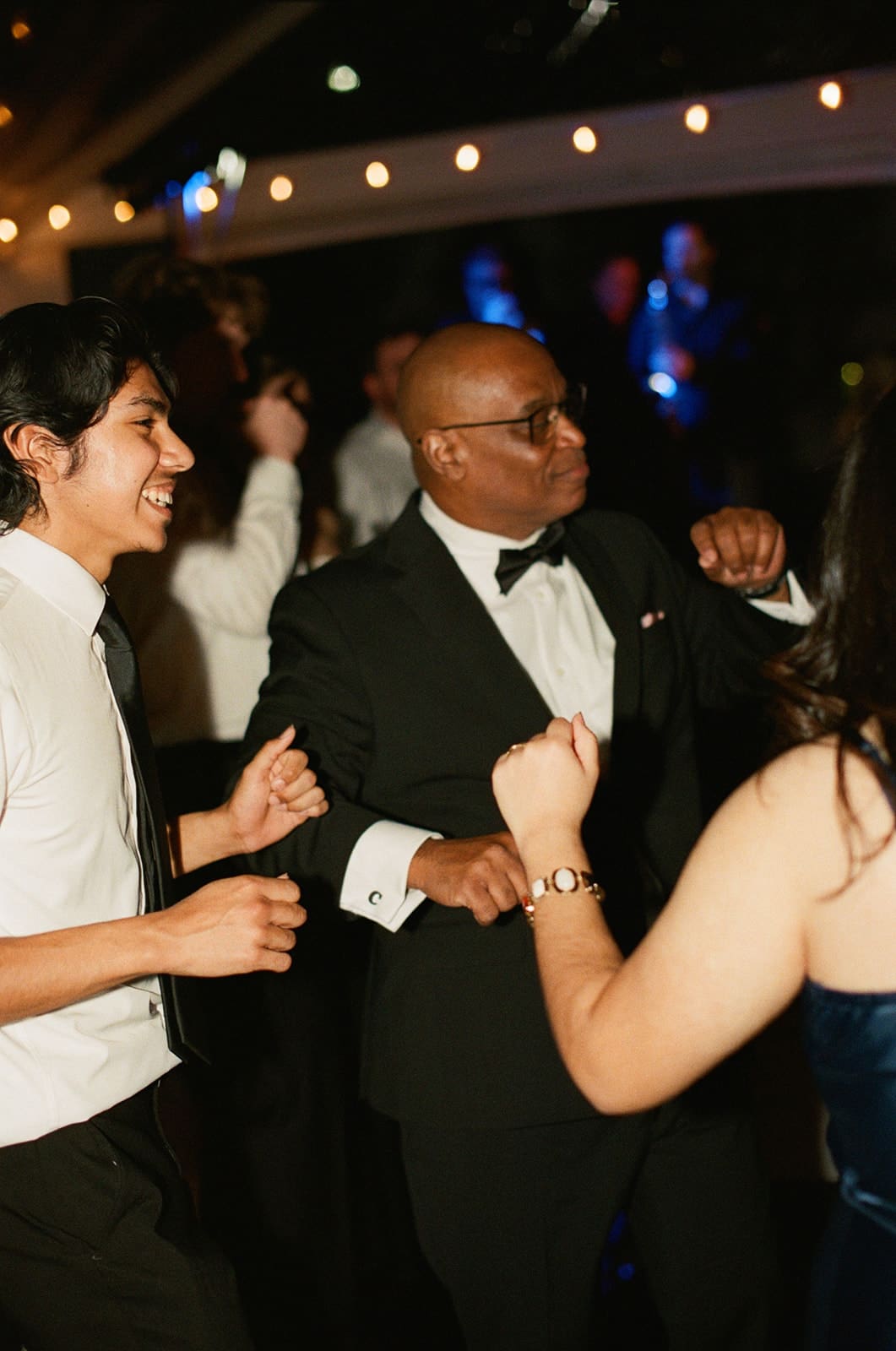 A group of people, dressed in formal attire, laugh and celebrate together at an indoor event or party.
