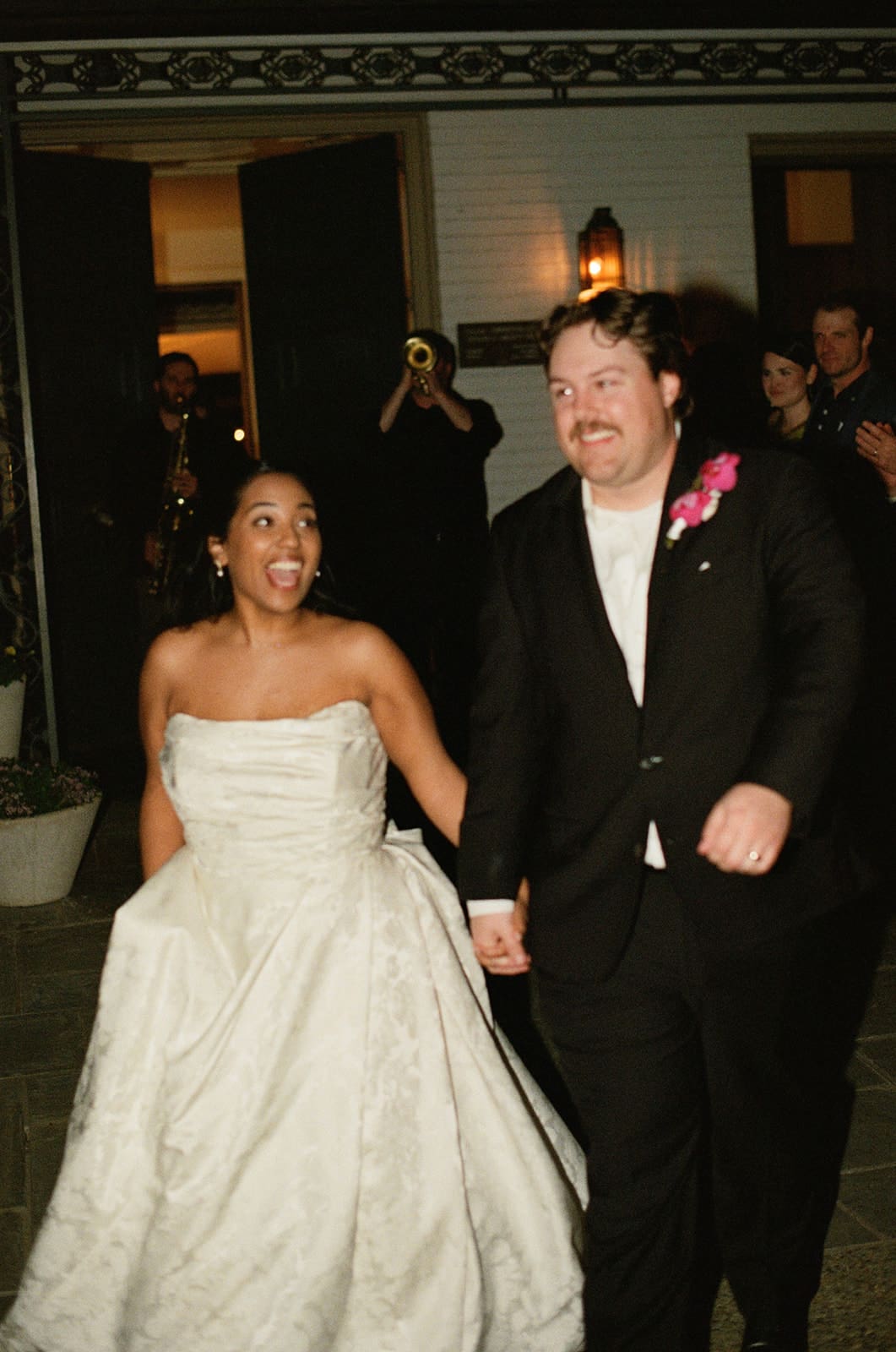 A group of people, dressed in formal attire, laugh and celebrate together at an indoor event or party.