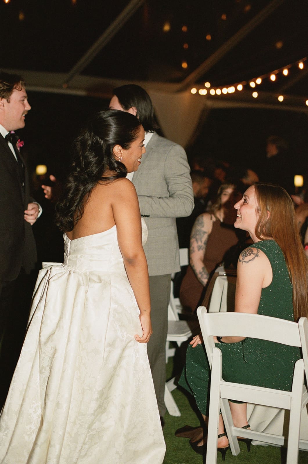 A group of people, dressed in formal attire, laugh and celebrate together at an indoor event or party.