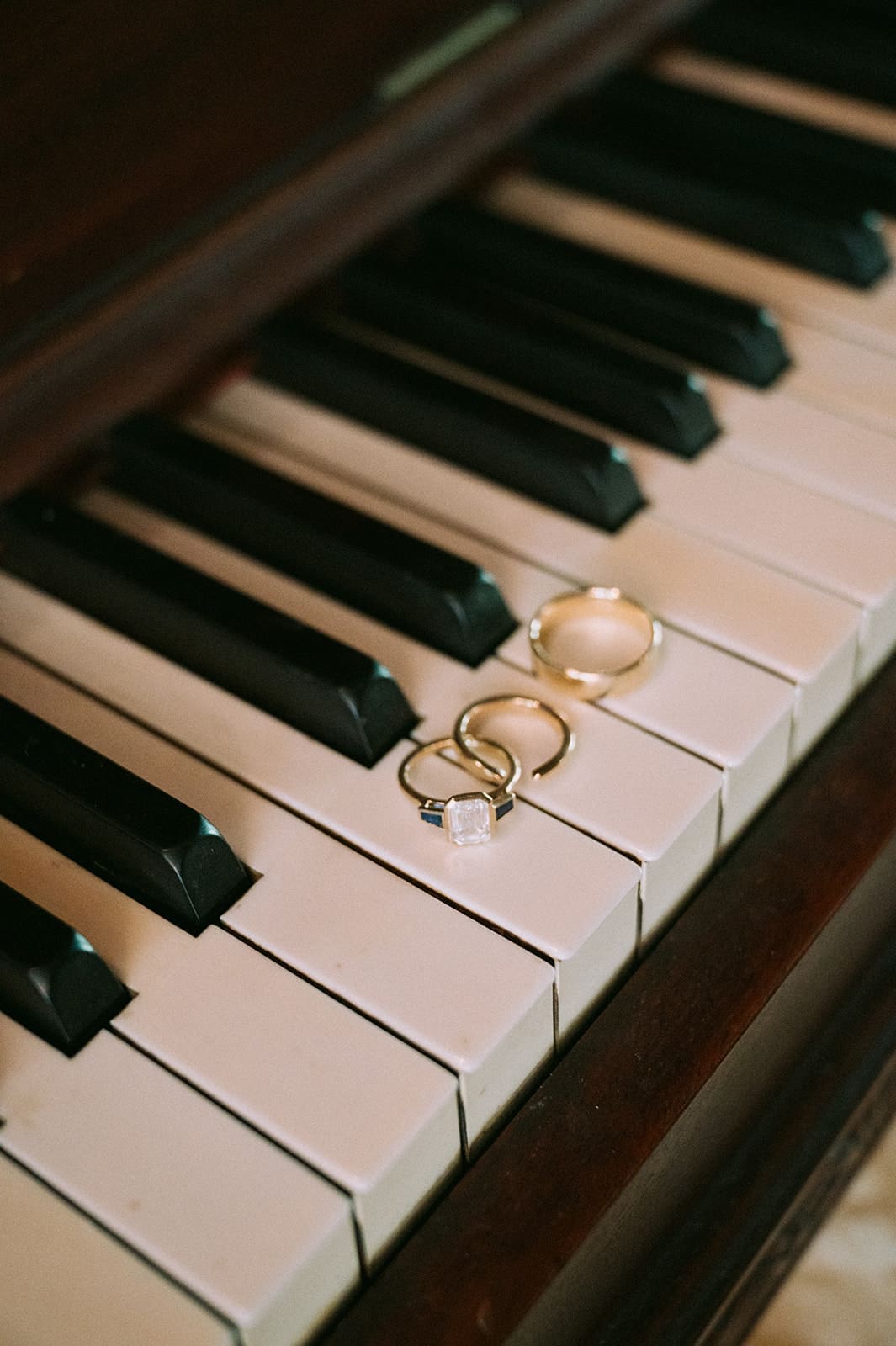 Three gold rings rest on the white keys of a piano keyboard.
