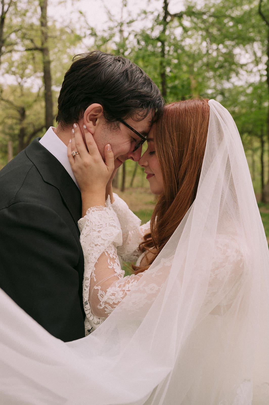 A bride and groom stand facing each other outdoors, holding hands, with an officiant reading between them during a wedding ceremony at An Intimate Backyard Wedding in Dallas