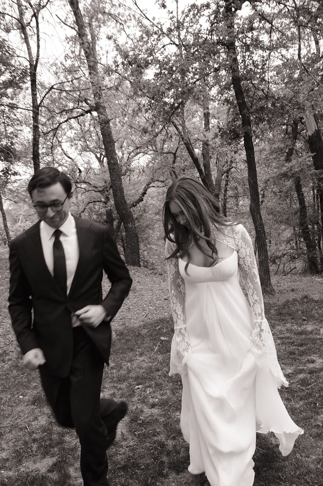 A bride and groom stand facing each other outdoors, holding hands, with an officiant reading between them during a wedding ceremony at An Intimate Backyard Wedding in Dallas