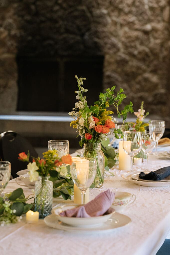Tables with white tablecloths and black chairs are set for an event in a rustic room with wooden beams and natural light | 9 Wedding Venues in Oregon for an Intimate Celebration