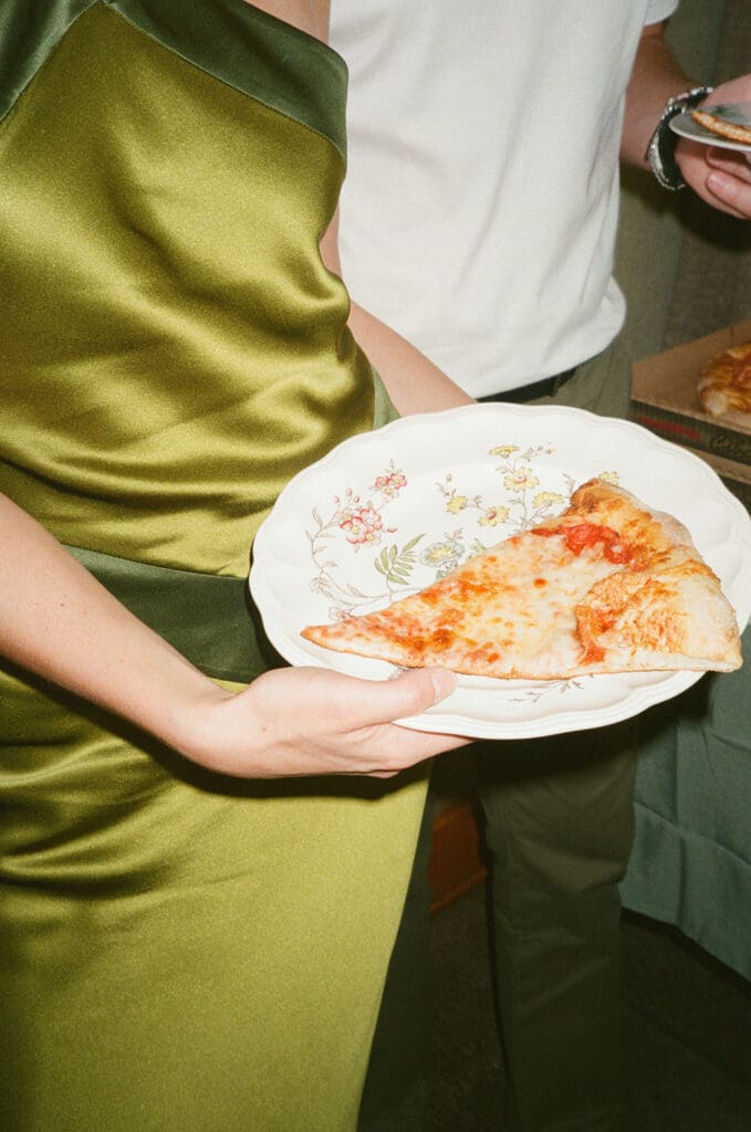 Person in a green satin dress holding a floral plate with two slices of pizza; another person stands nearby holding a phone | 9 Wedding Venues in Oregon for an Intimate Celebration