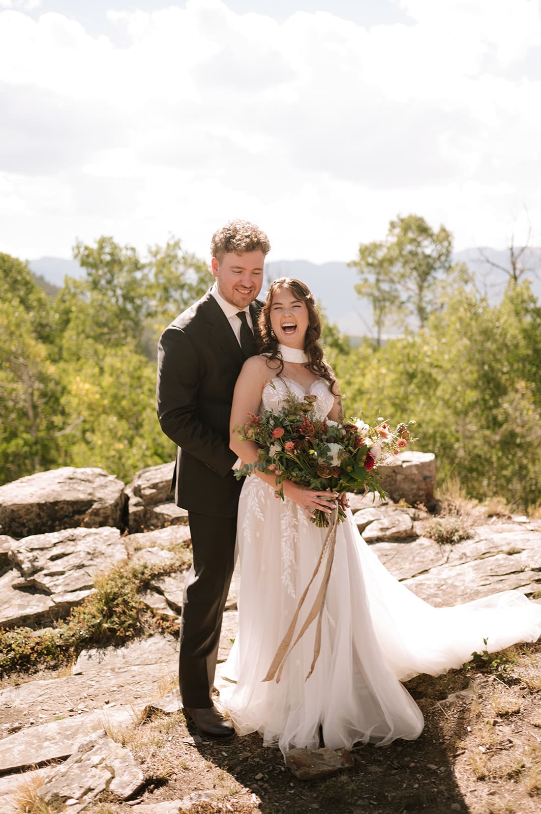 Bride and groom laughing together during wedding portraits with the Colorado mountains in the background