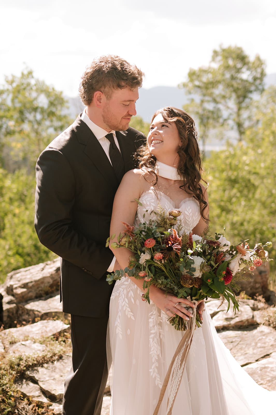 Newlyweds smiling together with a colorful bridal bouquet at a small wedding venue in Colorado