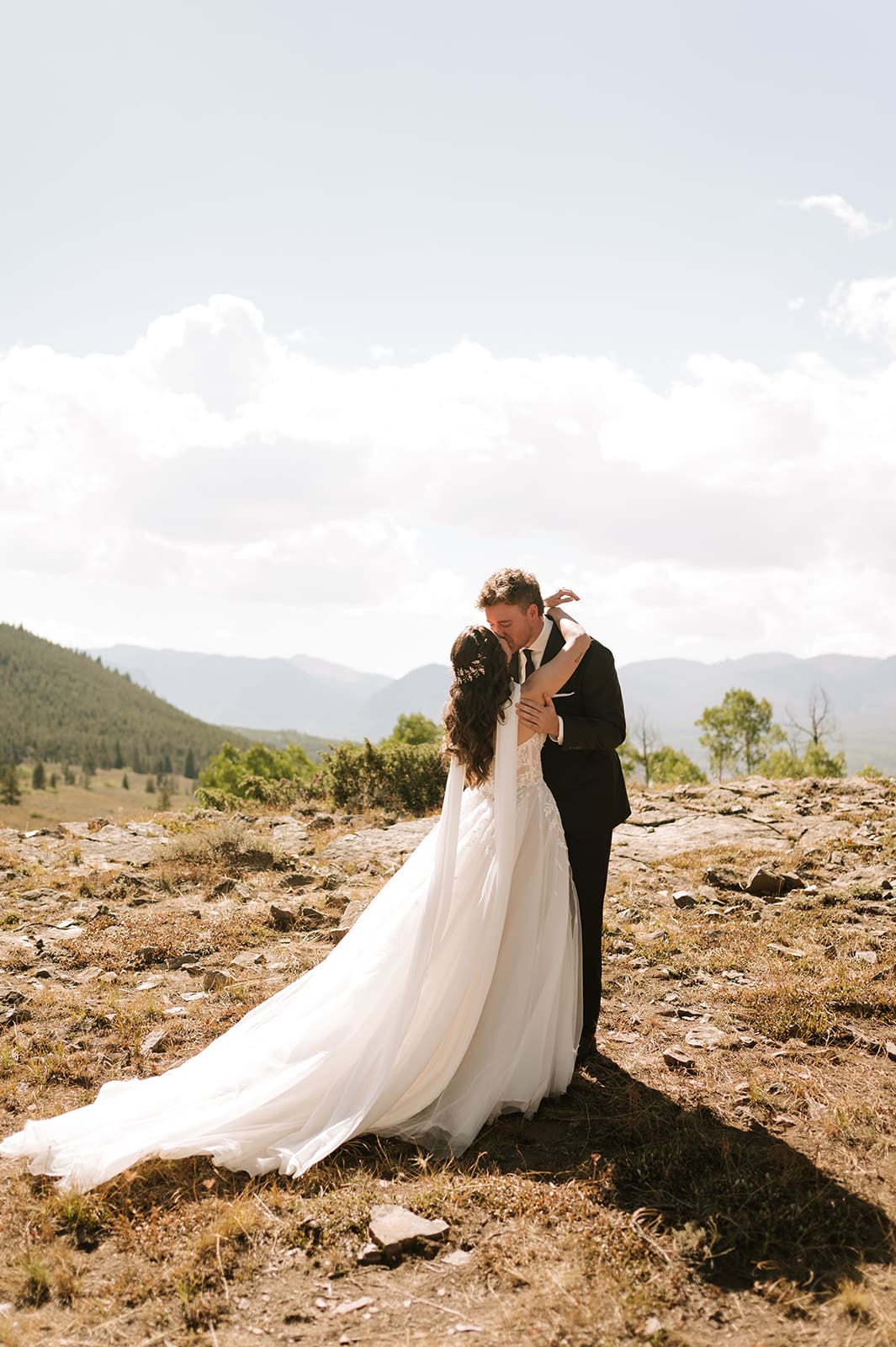Bride and groom sharing a kiss with Colorado mountain views at one of the small wedding venues in Colorado